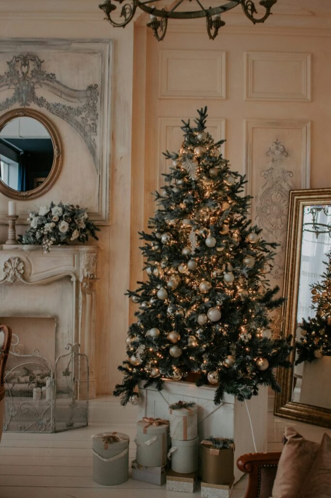 Salón clásico con molduras blancas, chimenea y árbol de Navidad con luces doradas y regalos a sus pies