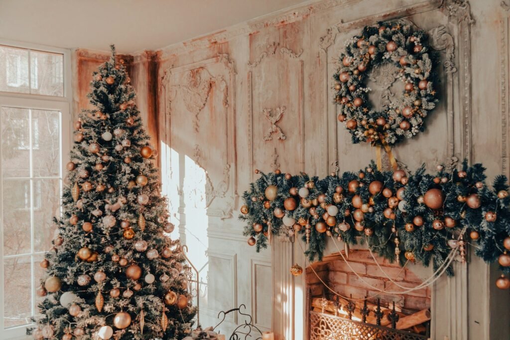 Árbol de Navidad con bolas cobrizas junto a una chimenea con guirnalda y corona