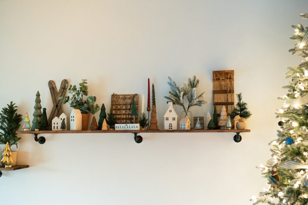 Estante de madera con casitas, árboles en miniatura y velas navideñas