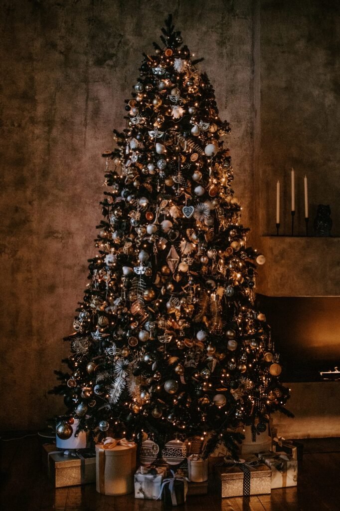 Árbol de Navidad con luces cálidas y regalos en un salón de paredes oscuras con velas