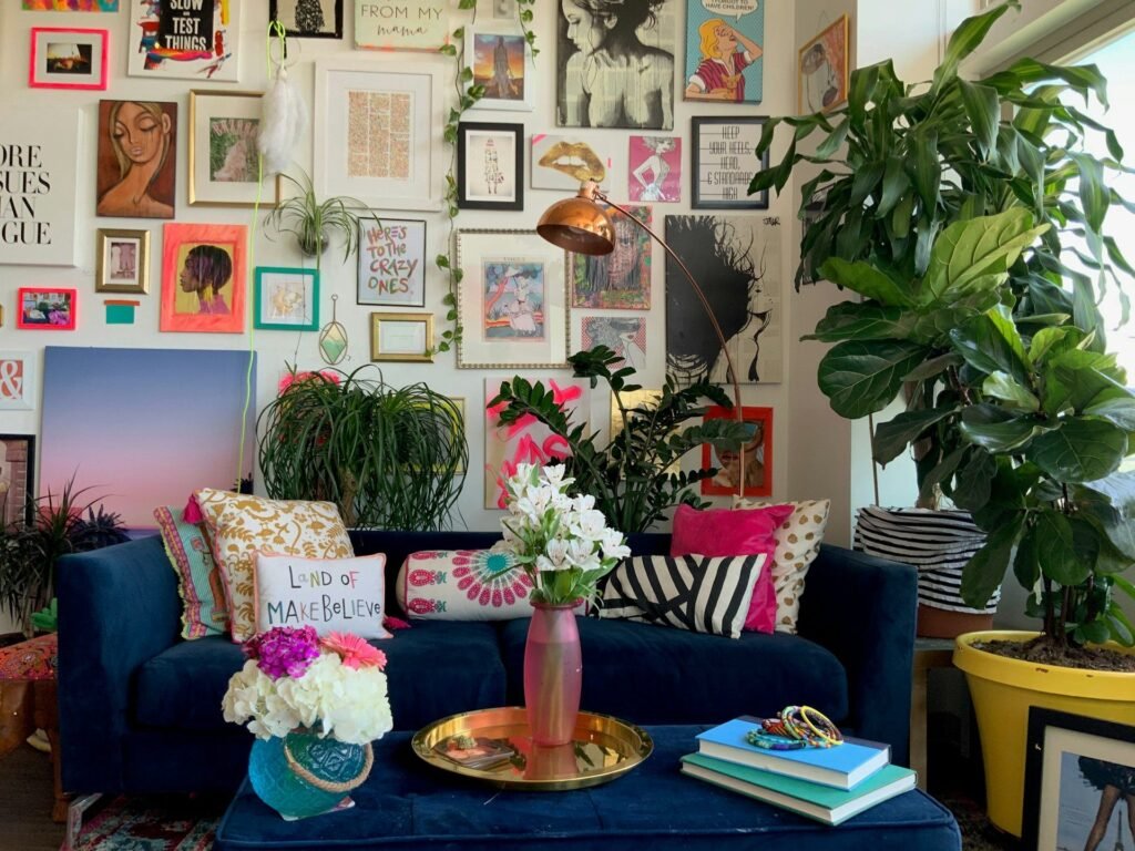 Salón colorido con pared de cuadros, sofá azul de terciopelo y plantas