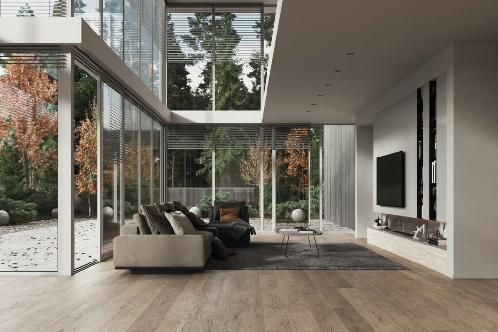 Salón abierto a un patio interior con grandes paños de vidrio y suelo de madera